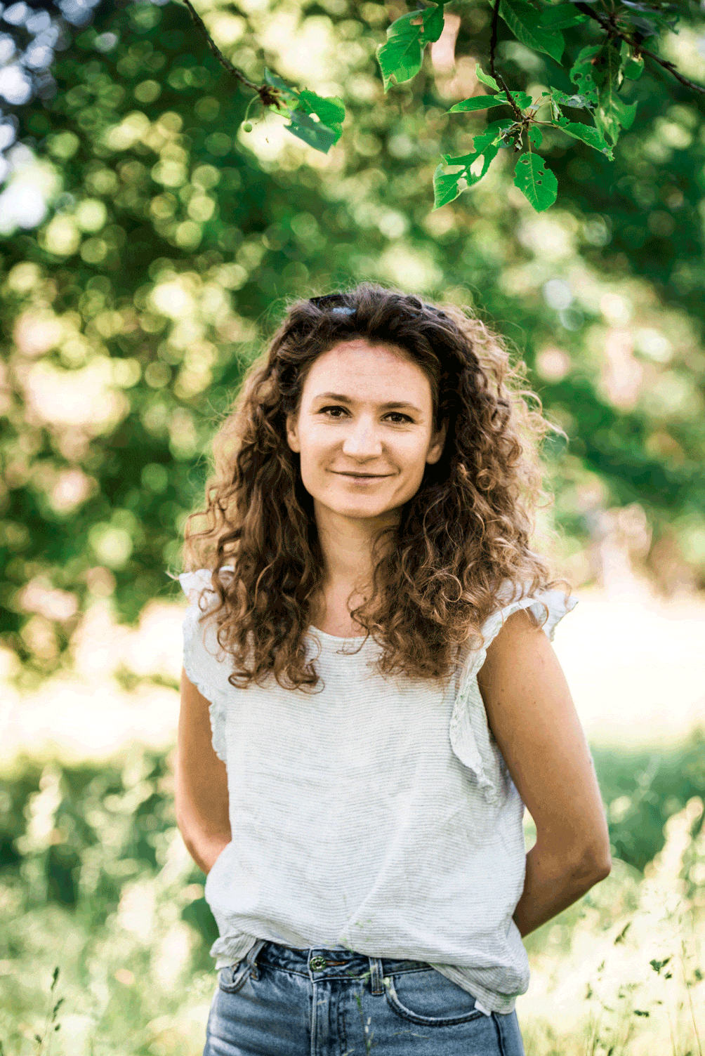 Portrait von Julia Okon im Grünen mit Blumen
