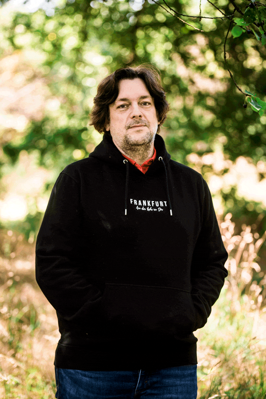 Portrait von Jens Best im Grünen mit Laptop in der Hand