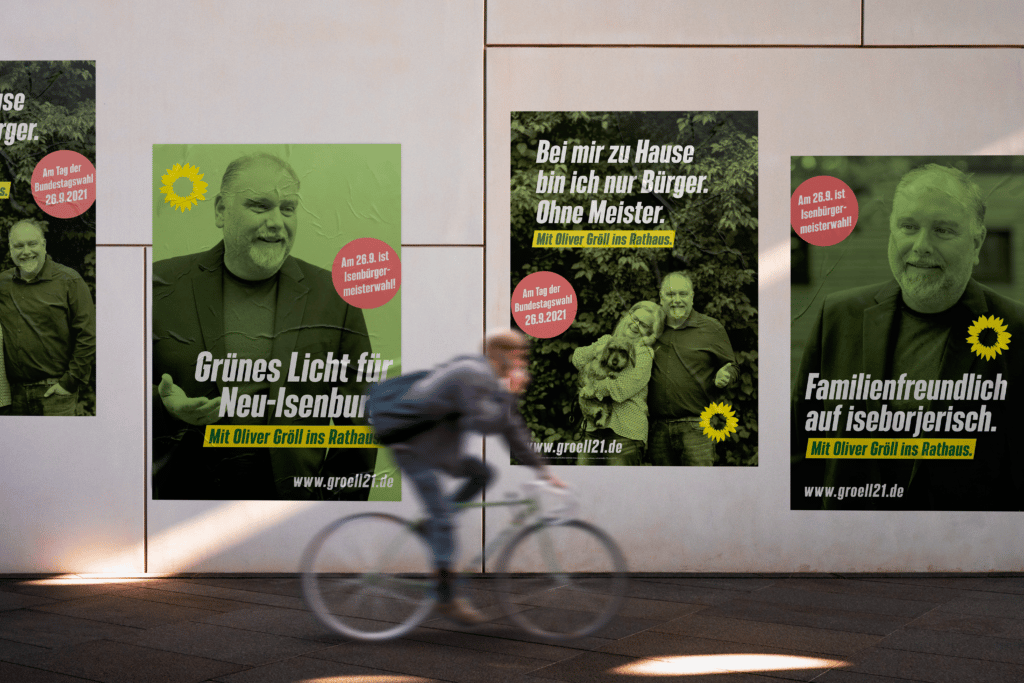 Fahrradfahrer fährt an Wahlplakaten des Oberbürgermeister Kandidaten der Grünen für Neu-Isenburg vorbei
